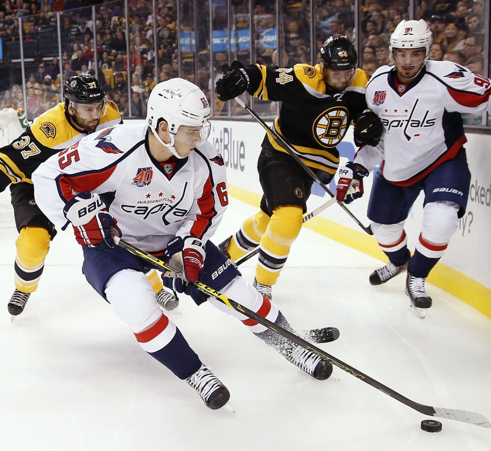 Washington left wing Andre Burakovsky controls the puck as Boston Bruins center Patrice Bergeron, left, moves in during the first period of Saturday night’s game in Boston, won by the Capitals.