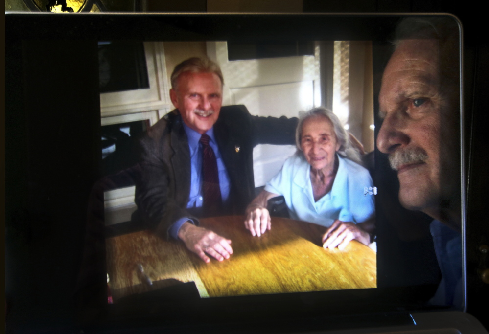 James Caccavo is reflected in his computer screen, next to a photograph of him with his elderly neighbor Sarah Cheiker, taken in 2012 at a health care center in Fryeburg, Maine, where she is currently living. Cheiker, now 89, disappeared in 2008 from her home in Los Angeles that was later bulldozed and replaced by a bigger house.