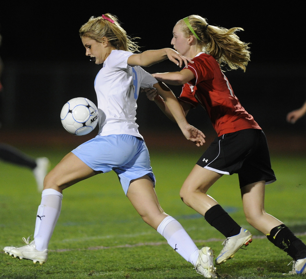 Windham’s Melissa Morton, left, plays a high ball while pressured by Scarborough’s Bryce Nitchman. Each team scored a first-half goal in the match that ended in a 1-1 tie.