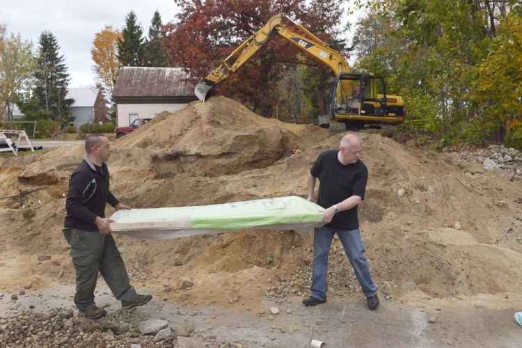Sgt. Steven Thistlewood, left, of the York County Sheriff’s Office and local funeral director Joe Watson carry out remains found during an excavation behind Cornish Town Hall. The graves were supposed to have been relocated in the 1920s.