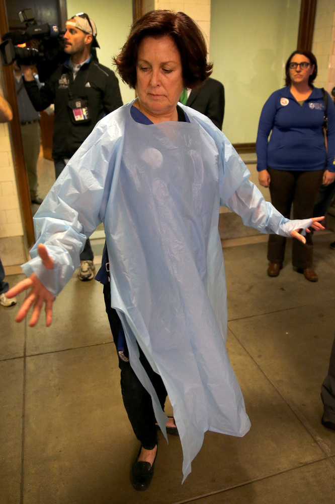 Nurse Katie Murphy, who works at Brigham and Women’s Hospital in Boston, models a standard precaution gown, outside the committee hearing room as the Legislature’s public health committee held a Statehouse hearing Thursday to assess the state’s readiness to deal with Ebola.