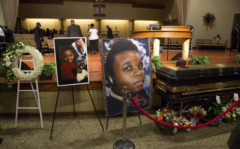 Photos surround Michael Brown’s casket Aug. 25 in St. Louis, Mo. A state grand jury is considering charges against the white police officer who shot him.
