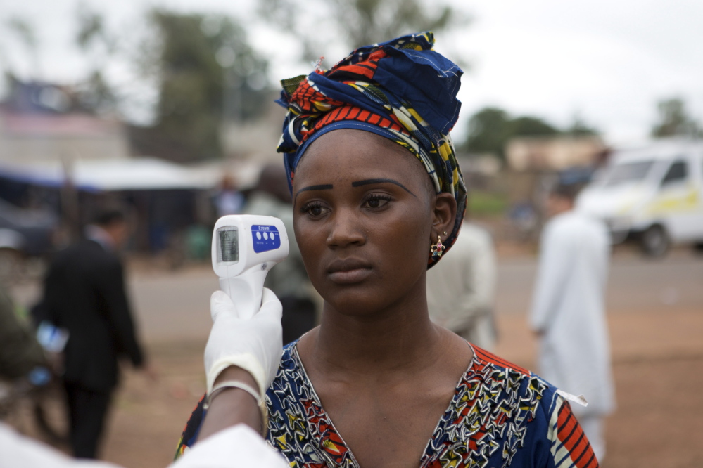 A health worker checks the temperature of a woman entering Mali from Guinea earlier this month. A World Health Organization draft document blames incompetent staff and other factors for an inadequate response to the “perfect storm” that was brewing.