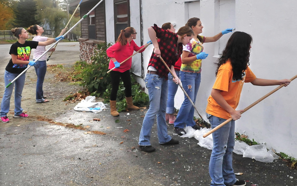 Carrabec High School seniors and art students paint over a mural at a North Anson building in preparation to paint another mural on it as part of a community service project.
