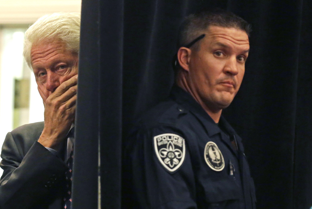 A Baton Rouge police officer, right, stands post while former President Bill Clinton watches from backstage before he is introduced to speak at a campaign event for Sen. Mary Landrieu, D-La., in Baton Rouge, La., on Monday.