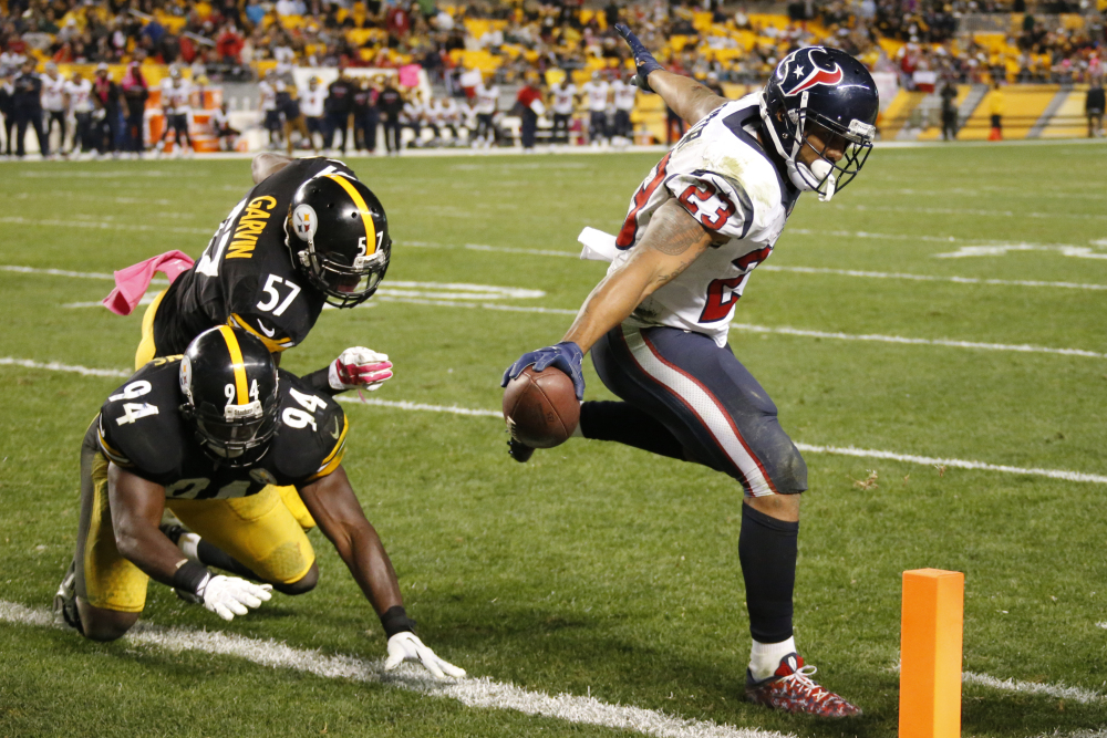 Houston Texans running back Arian Foster (23) reaches the ball across the goal line for a touchdown after eluding tackle by Pittsburgh Steelers inside linebackers Lawrence Timmons (94) and Terence Garvin (57) during the final minutes in the fourth quarter of an NFL football game in Pittsburgh.