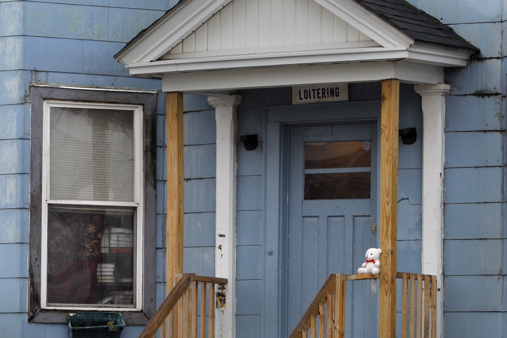 A stuffed teddy bear sits on the front porch of 125 Pierce St. in Lewiston the day after an 11-month-old baby died in the bathtub in the apartment at left.