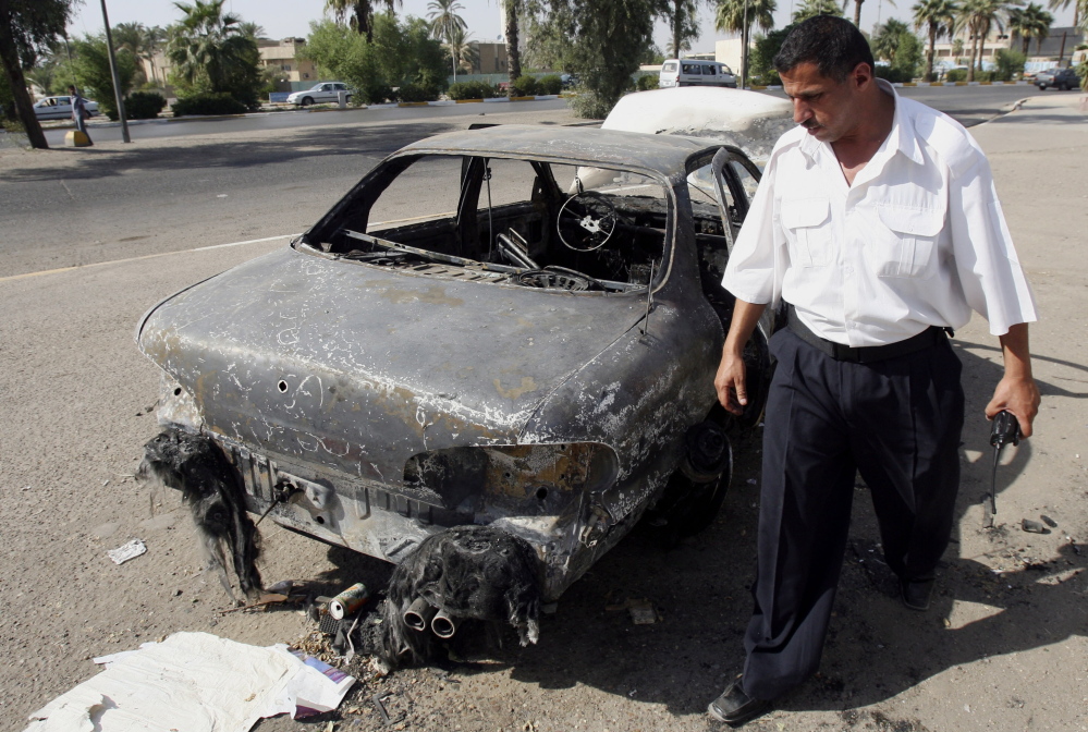 An Iraqi policeman inspects a car destroyed Sept. 16, 2007, by a Blackwater Worldwide security detail in Baghdad, Iraq, in this Sept. 20, 2007 file photo.