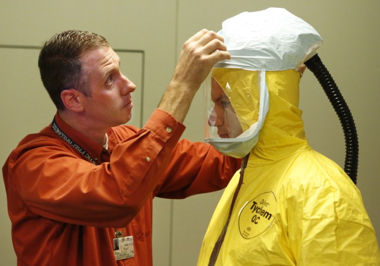 Industrial hygienist John Swiger, left, and emergency management coordinator Brian Dougher demonstrate how Maine Med workers would suit up to treat a patient with Ebola.