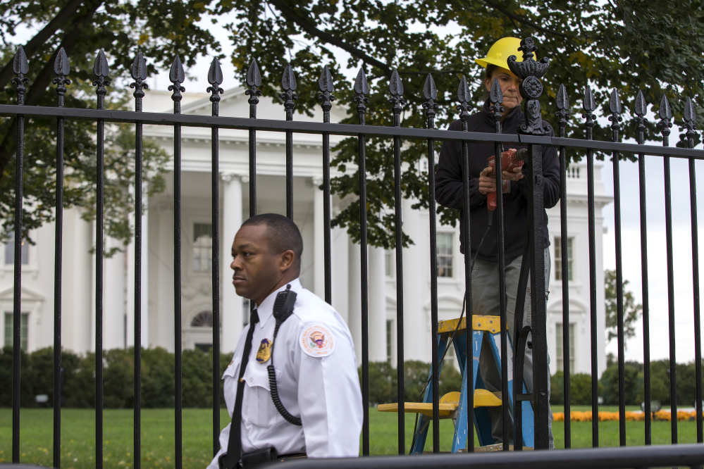 A Secret Service police officer walks outside the White House on Thursday as a maintenance worker does fence repairs as part of a previous restoration project. A 23-year-old Maryland man who climbed over the fence Wednesday night has been charged with unlawfully entering the restricted grounds of the White House and harming two police dogs.