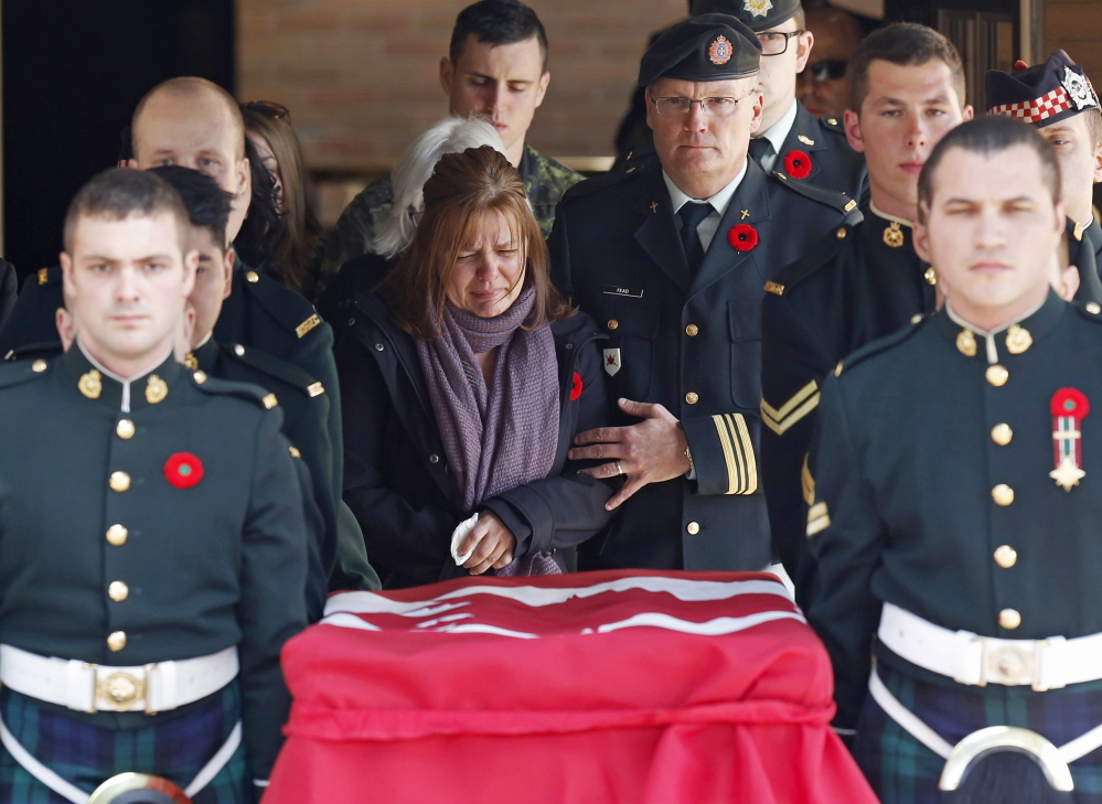 Kathy Cirillo, center, mother of Cpl. Nathan Cirillo, follows pallbearers carrying her son’s casket from a funeral home in Ottawa on Friday. Cirillo was killed during a shooting incident at the Canada War Memorial in Ottawa on Wednesday.