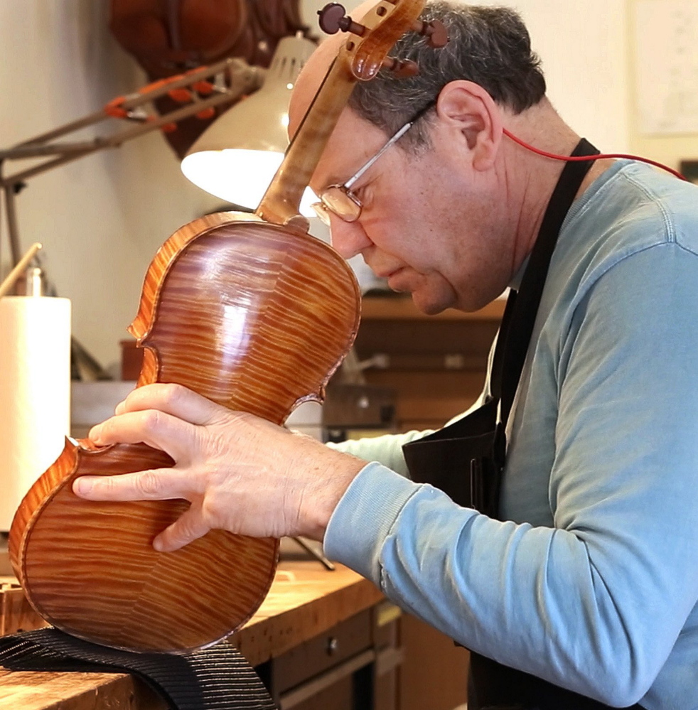 In his Portland workshop,  Jonathan Cooper repairs a violin owned by Mark O’Connor.