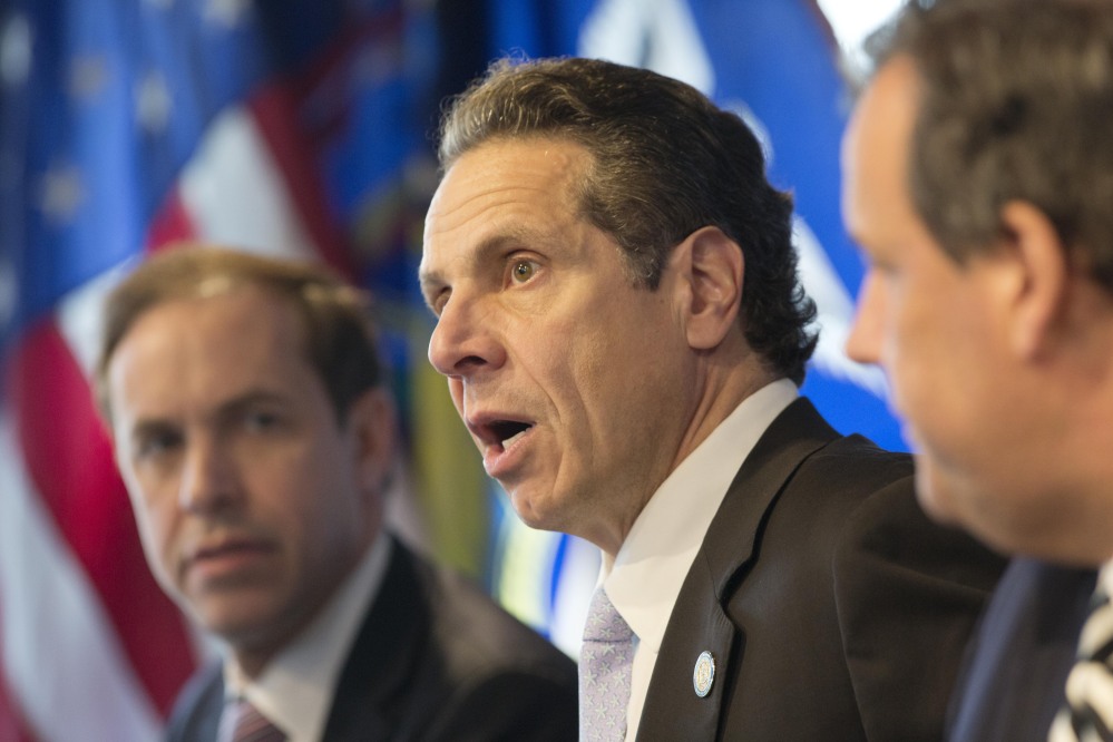 New York Governor Andrew Cuomo, center, speaks at a news conference, Friday in New York. At left is Dr. Howard Zucker, acting commissioner of the New York State Department of Health, and New Jersey Governor Chris Christie is at right.