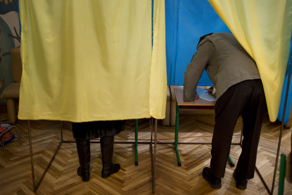 People fill their ballots at a polling center during voting in the parliamentary elections in Kiev, Ukraine, Sunday, Oct. 26, 2014.  Voters in Ukraine headed to the polls Sunday to elect a new parliament, overhauling a legislature tainted by its association with ousted President Viktor Yanukovych.