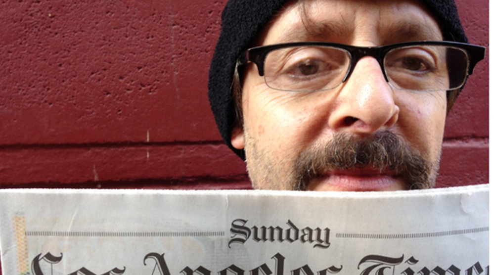 Judd Nelson holds up Sunday’s Los Angeles Times as his agent takes a picture to prove Nelson is still alive.