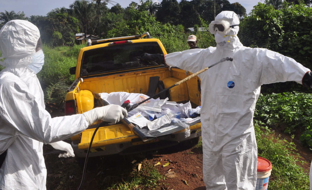 A health worker sprays disinfectant onto a colleague after they worked with the body of a suspected Ebola victim on the outskirts of Monrovia, Liberia, on Monday. Such workers “should not be stigmatized,” the U.N. Secretary-General said.