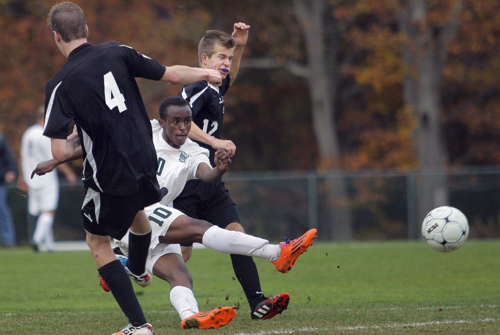 Ahmed Mohamed of Waynflete sneaks a shot through St. Dominic defenders Adam Vining, left, and Connor Samson during a Western Class C quarterfinal on Tuesday afternoon in Portland. The Flyers won 3-0, recording their 10th shutout of the season.