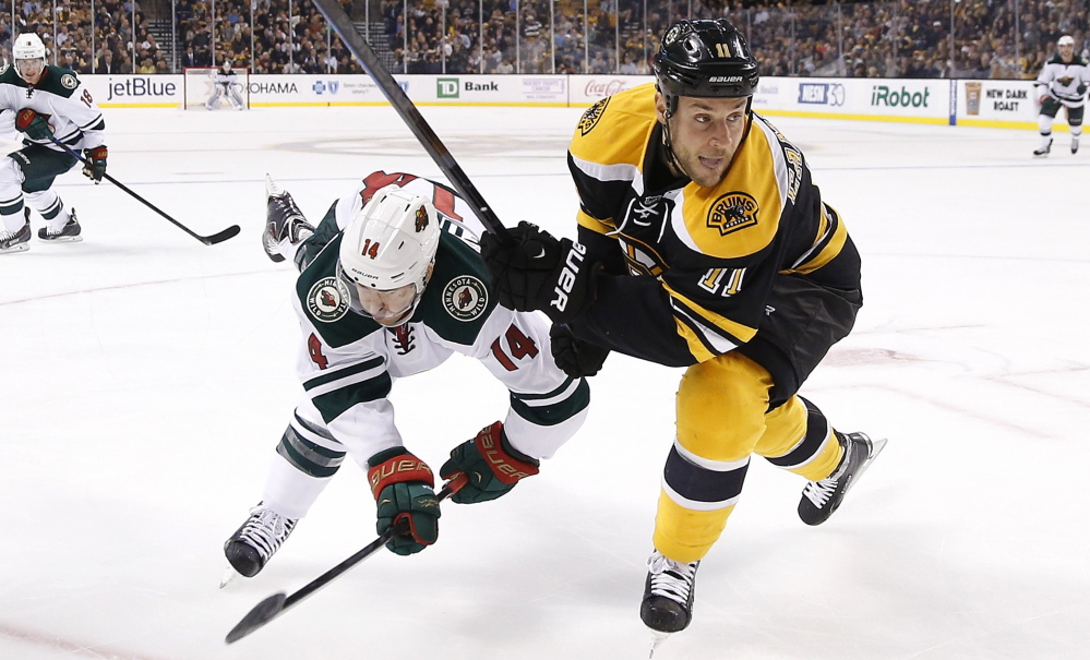 Justin Fontaine of the Wild falls to the ice while battling Bruins center Gregory Campbell during the first period of Tuesday’s game in Boston. Minnesota rode a furious third-period comeback to a 4-3 victory.