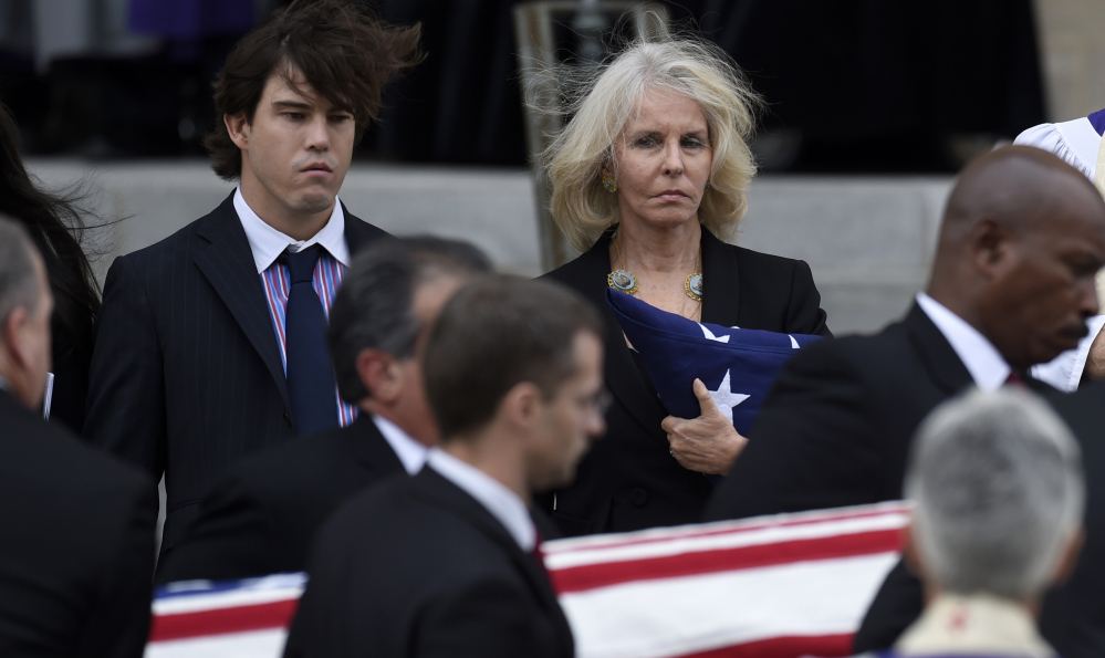 Ben Bradlee’s widow, Sally Quinn, and son Quinn Bradlee watch as the casket is moved from the church on Wednesday.