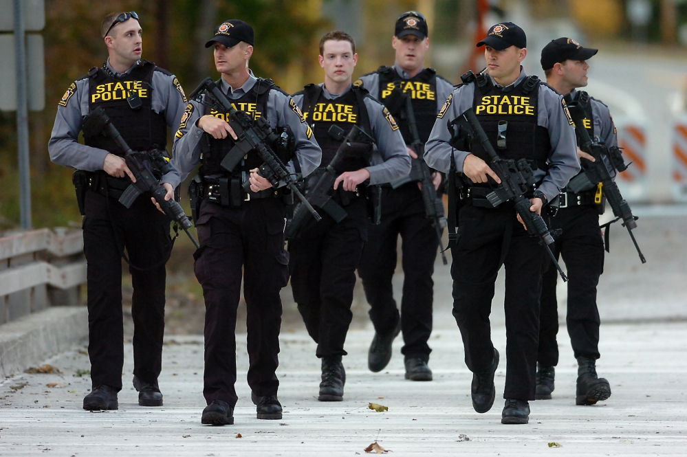 Pennsylvania State Police troopers walk along Route 191 after searching woods in Henryville, Pa., on Monday during the  manhunt for suspected killer Eric Frein. Police said late Thursday that they have Eric Frein in custody.
