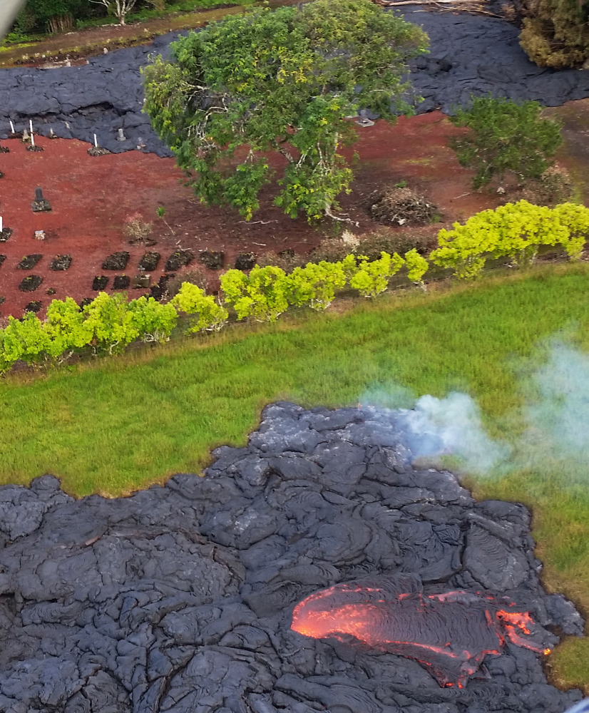 Lava partially covers a cemetery near the town of Pahoa on the Big Island of Hawaii. The lava is crawling toward a major road, threatening to further isolate the community.
