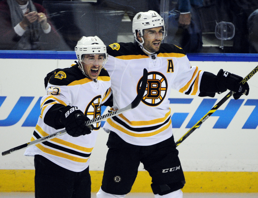 The Boston Bruins’ Brad Marchand (63) celebrates his game-winning goal in overtime with teammate Patrice Bergeron on Thursday night in Buffalo, N.Y.