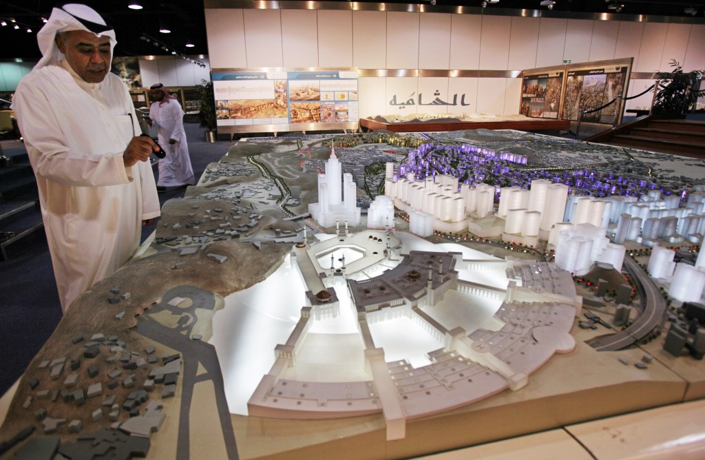 In this photo taken May 11, 2014, Essam Kalthoum, left, managing director of the Bawabat Makkah Company, which oversees several projects around Mecca, shows a prototype of what the heart of Mecca will look like after construction around the Grand Mosque is complete. The Associated Press