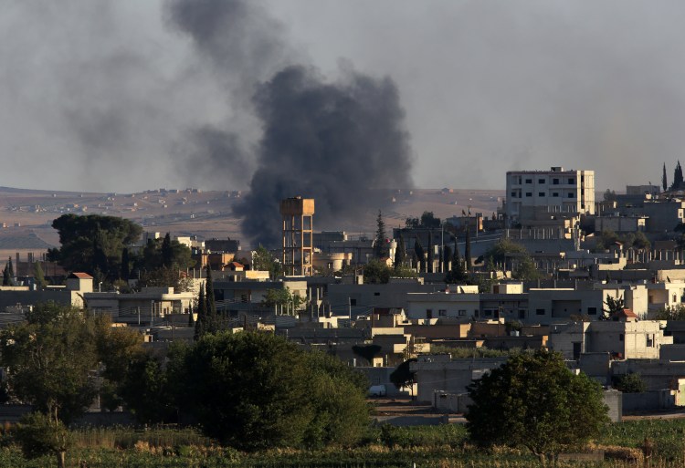 Smoke rises after a mortar shell landed in the south of the city center of Syrian Kurdish town of Kobani, seen from the Turkish side of border, as thousands of new Syrian refugees from Kobani arrive in Suruc, Turkey on Wednesday,. The Associated Press