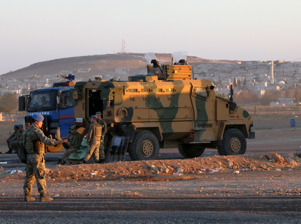 Turkish soldiers stand guard at a checkpoint as Syrian refugees from Kobani arrive at the Turkey-Syria border crossing of Mursitpinar near Suruc, Turkey, late Wednesday. The Associated Press