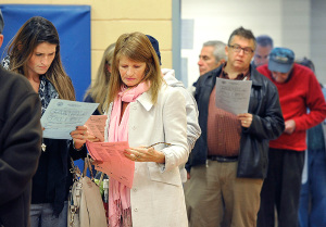 The bear-hunting debate brought Elisabeth Harding (in white coat) out to vote. She studies a sample ballot before voting at the Boys and Girls Club in South Portland.