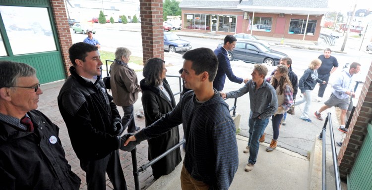Local candidates shake hands with voters as they enter the American Legion on College Avenue in Waterville on Tuesday.