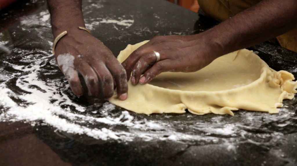 Marcus Samuelsson presses dough for his Garam Masala Pumpkin Tart into a tart pan, draping the dough over the edges. He saves the extra bits of dough to make crumbles.