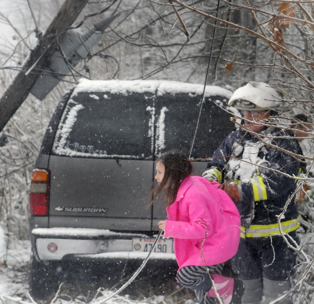 Farmingdale Assistant Fire Chief Mike LaPlante escorts Ella Cotnoir, 8, beneath power lines that trapped her family Sunday in their SUV on Maple Street in Farmingdale for over an hour. Central Maine Power shut off the power and Farmingdale firefighters got the Cotnoir family out. The West Gardiner family members, who were returning from church, were uninjured.