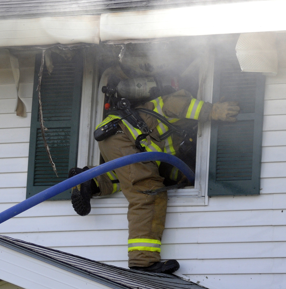 A firefighter climbs through a second floor window Sunday into a residence that caught fire in Gardiner. Crews from several area communities responded to the blaze that caused extensive interior damage, according to firefighters. No injuries were reported. Andy Molloy / Kennebec Journal Staff Photographer
