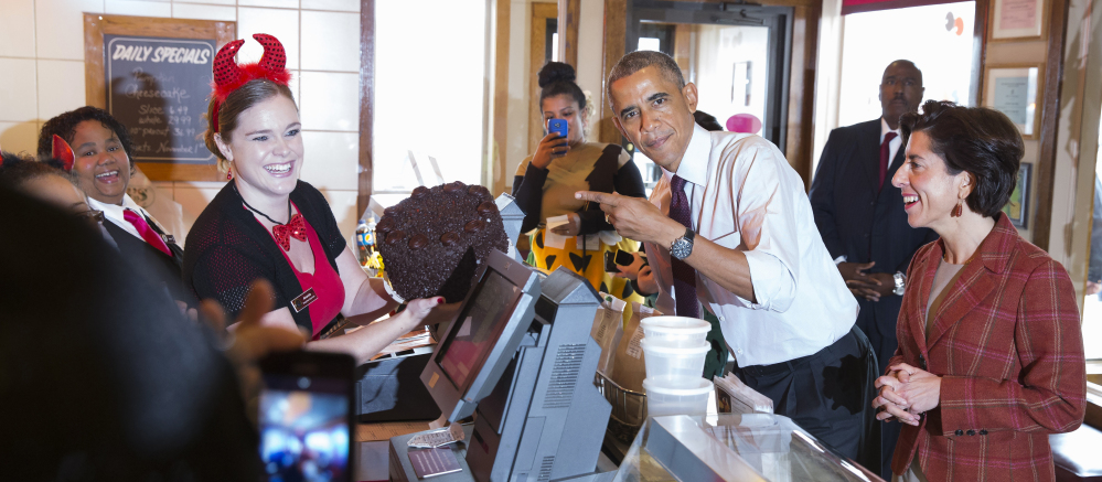 President Obama points to a “Death by Chocolate” cake he ordered Friday at Gregg’s Restaurant and Pub in Providence, R.I. At right is Rhode Island Democratic gubernatorial candidate Gina Raimondo.