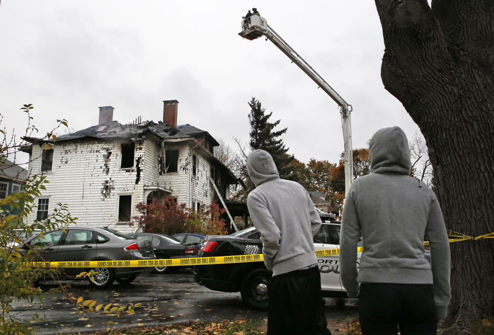 Neighbors look at the scene of a fatal apartment building fire, Saturday, Nov. 1, 2014, in Portland, Maine. The fire swept through a two-apartment building housing students from the University of Southern Maine on Saturday morning, killing four people and critically injuring one, authorities said. They were still trying to account for several people who had been at a Halloween party at the building the night before. (AP Photo/Robert F. Bukaty)