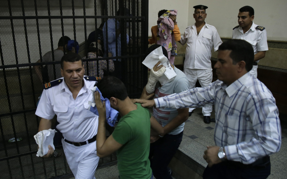 Egyptian men convicted of “inciting debauchery” after an alleged same-sex wedding party cover their faces as they leave court in Cairo, Egypt, on Saturday.