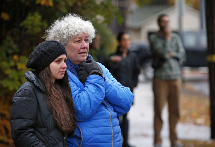 Neighbors watch as a body is removed from the scene of a fatal apartment building fire in Portland, Maine on Saturday, Nov. 1, 2014. Earlier in the morning, a fatal fire swept through a two-apartment building housing students from the University of Southern Maine. (AP Photo/Robert F. Bukaty)