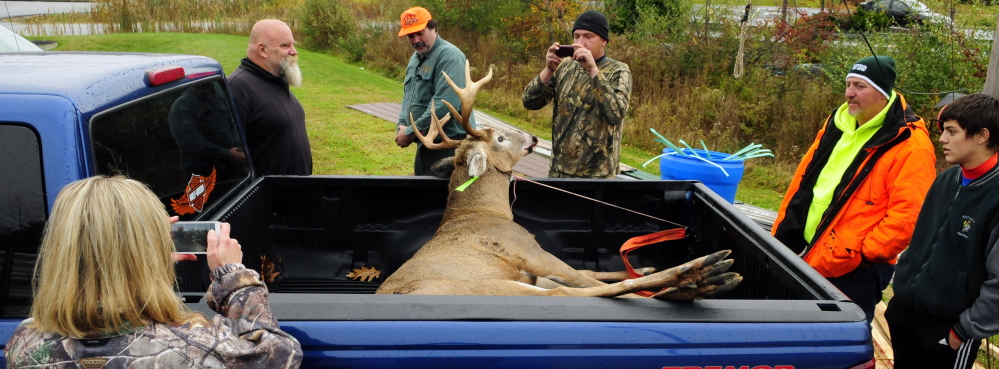 A buck weighing more than 200 pounds, shot by Mike Bennett, center in an orange hat, draws a lot of attention Saturday at Audette’s Hardware in Winthrop.