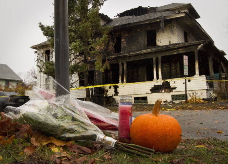 A shrine starts to grow Sunday morning on Noyes Street near the scene of a house fire that claimed five lives Saturday. 