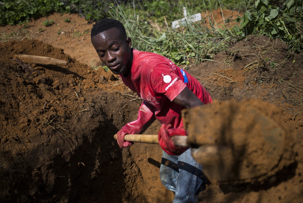 A member of a hospital burial team digs a grave for a child who had died of Ebola earlier that day in Ganta, Liberia. Awareness has improved, but experts fear some victims will avoid treatment centers and disappear into remote areas.