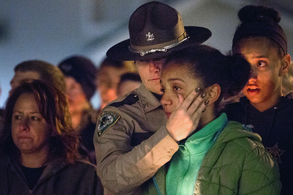 CORNISH, ME - NOVEMBER 3: Deputy Christina McAllister with the Oxford County Sheriff's Department wipes tears away from the face of her daughter, Viktoria Sugars, 11, as McAllister's other daughter, Cayla Sugars, 14, looks on, during a vigil at Call's Shop 'n Save on Route 25 in Cornish Monday evening, November 3, 2014, for the victims of a car crash that killed two teenagers in Hiram early Saturday morning. Andrew Stanley, 18, of Porter, died at the scene, and Isaac Moore, 19, of Parsonsfield, died at Maine Medical Center. McAllister is the school resource officer at Sacopee Valley High School where both of the victims graduated from. (Photo by Gabe Souza/Staff Photographer)