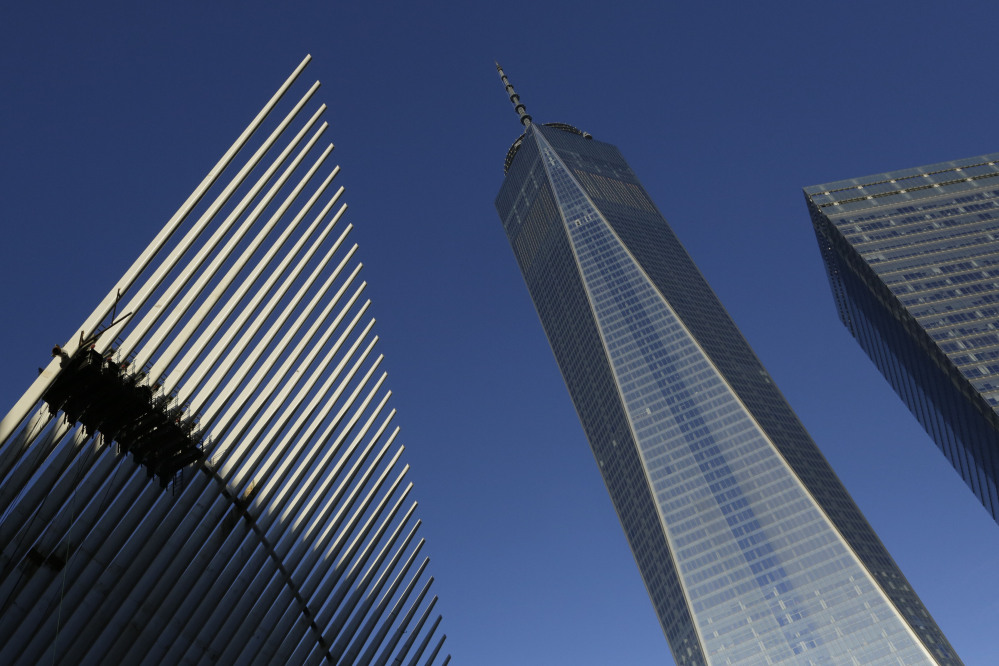 One World Trade Center stands between the transportation hub, left, still under construction, and 7 World Trade Center in New York. Thirteen years after the 9/11 terrorist attacks, the resurrected One World Trade Center opened for business Monday as the publishing giant Conde Nast started moving in.