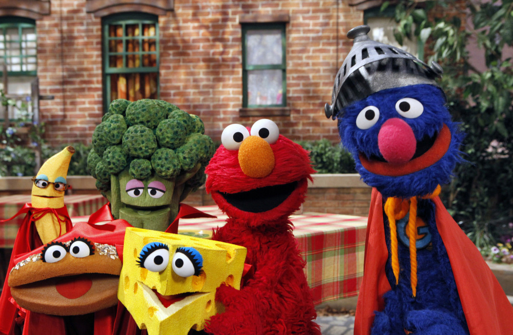 This June 22, 2010 file photo released by Sesame Workshop, “Sesame Street” characters Elmo, second from right, and Super Grover, right, pose with four new muppets representing healthy food groups; fruits, vegetables, dairy, and grains as part of their “Food For Thought:  Eating Well on a Budget” initiative in New York.