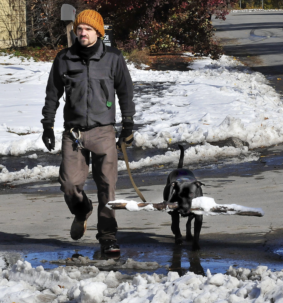Timothy Wing walks his dog Ruby, who has a good hold on a snow-covered stick in Waterville on Monday.