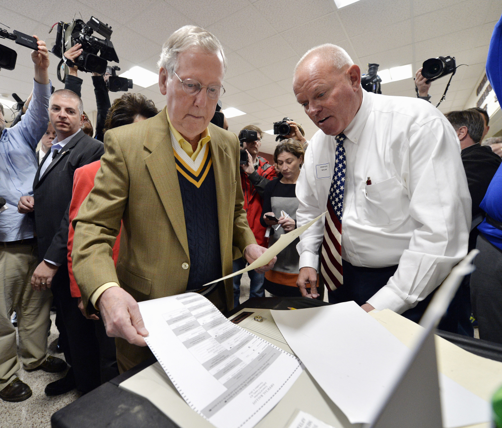Senate Minority Leader Mitch McConnell of Ky., left, casts his vote as poll worker William Comstock looks on in Louisville, Ky., Tuesday.