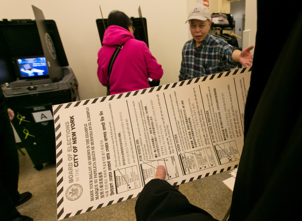 A voter carries her ballot Tuesday to be scanned at a polling place in New York’s Chinatown neighborhood.