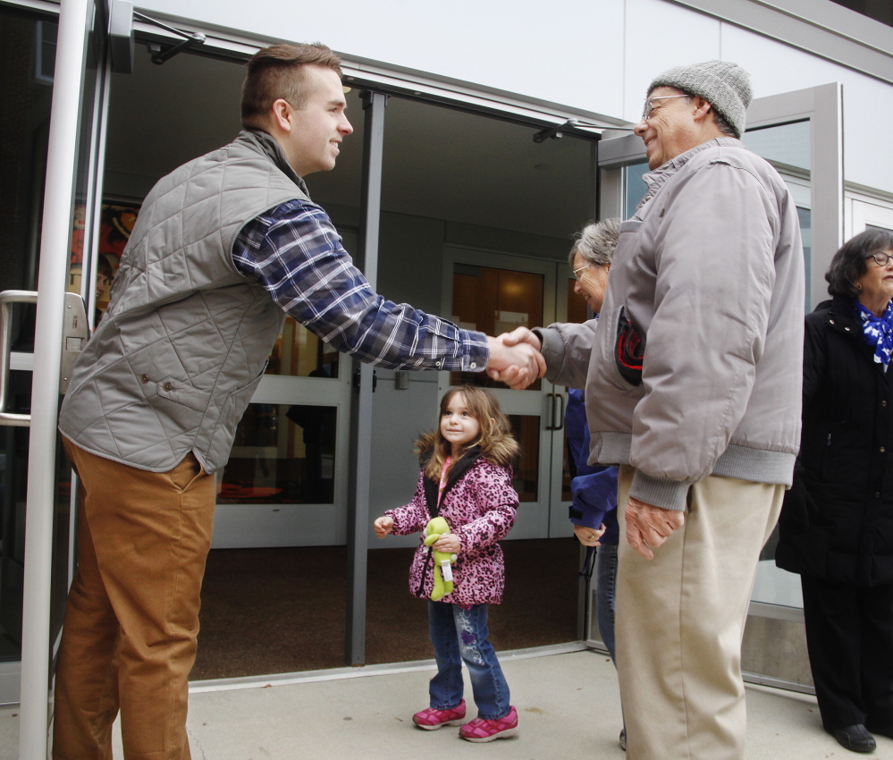 Ryan Fecteau, left, greets Conrad Houde, his wife, Jeanne, and their 3-year-old granddaughter, Aleisha, at Biddeford High School while campaigning for a seat in House District 11 on Tuesday.