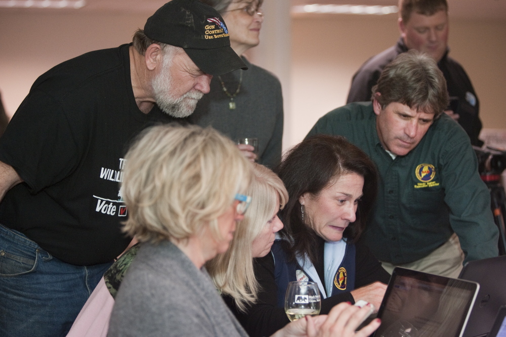 Keith Thompson of Morrill, left, a volunteer with the No on 1 campaign, Sportsmen’s Alliance of Maine President Cheryl Timberlake, second from right, and its Executive Director David Trahan, right, monitor online vote returns  at the Black Bear Inn in Orono.