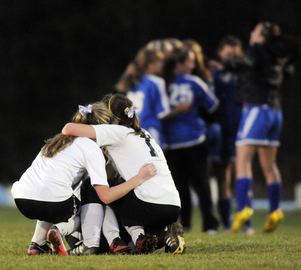 Maranacook players huddle as Sacopee Valley players celebrate their 1-0 victory in the Western C girls’ soccer title game Wednesday in Readfield.
